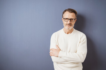 Serious senior man in white sweater looking at camera