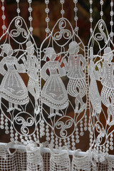 Traditional Bertonne lace curtains feature elegant dancers, showcasing craftsmanship on vertical...
