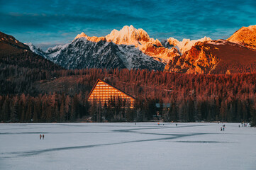 Cold Winter Sunset at Strbske pleso in Slovakia, Last orange light at the ridge of High Tatra Mountains in background. Adventure in winter mountains.