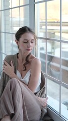 Beautiful young girl posing for the camera while sitting near a large window