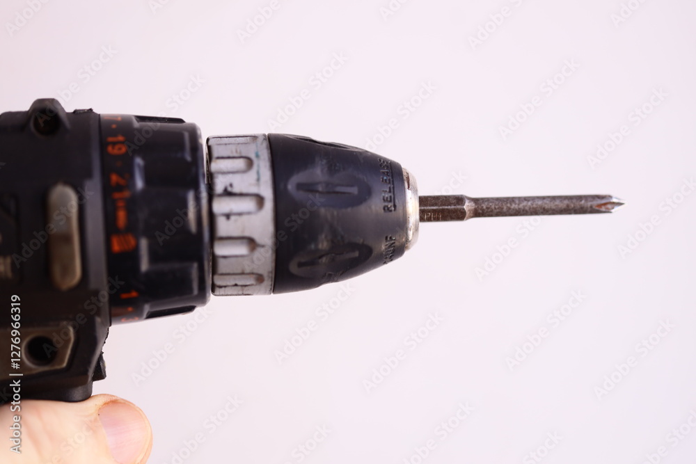 Poster a hand holds a drill bit with a screw in it, ready for use.