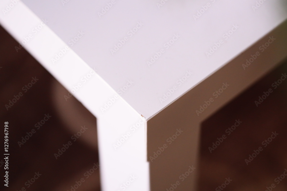 Poster a close-up of a simple white table with a single flower sitting on it, great for use in home decor o