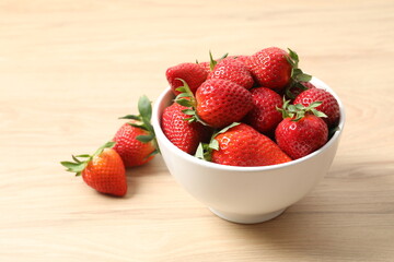 Delicious fresh red strawberries in a bowl on a wooden background