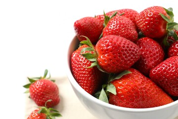 Delicious fresh red strawberries in a bowl on a wooden background