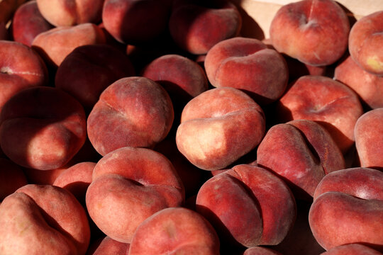 Fig peach crop. Lots of flat oval peaches at the local market as a background or food texture.