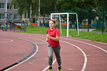 Fototapeta premium Attractive Caucasian boy runs around the stadium