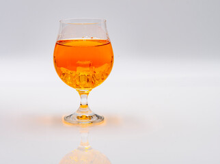 A delightful orange beverage is presented in a stylish glass, showcasing its vibrant color. The drink is set against a clean, minimalist background that emphasizes its appeal.