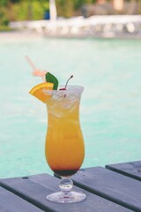 A nice cocktail, hat and sunglasses by the pool