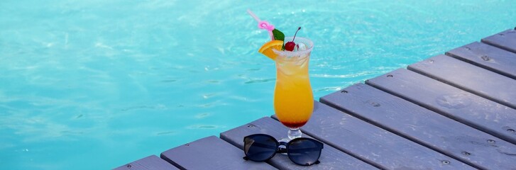 A nice cocktail, hat and sunglasses by the pool