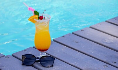 A nice cocktail, hat and sunglasses by the pool