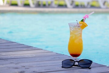 A nice cocktail, hat and sunglasses by the pool