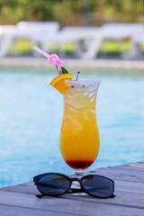 A nice cocktail, hat and sunglasses by the pool