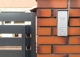 Modern Intercom Keypad on Brick Wall by Metal Gate