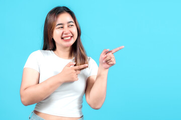 A smiling young woman in a white t-shirt playfully pointing with both hands, showcasing a cheerful...