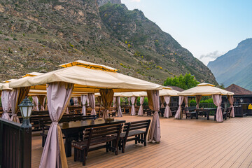 open-air restaurant in the mountains wooden floor tents over tables and benches. natural light