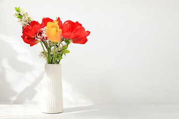 Beautiful spring blooming branches of bird cherry, cherry and tulips in a vase on an elegant background. Abstract floral composition and banner for the screen, Still life with space for text,