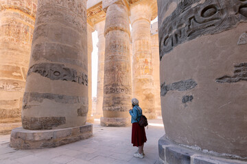 Woman traveler explores the ruins of the ancient Karnak temple in the city of Luxor in Egypt. Great...