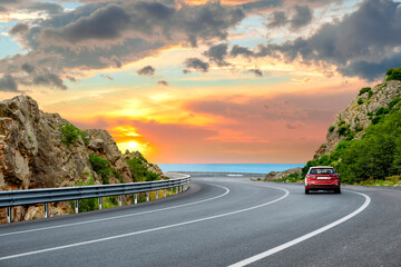 car driving on beautiful road in colorful sunset landscape in summer. Nature scenery on coastline...