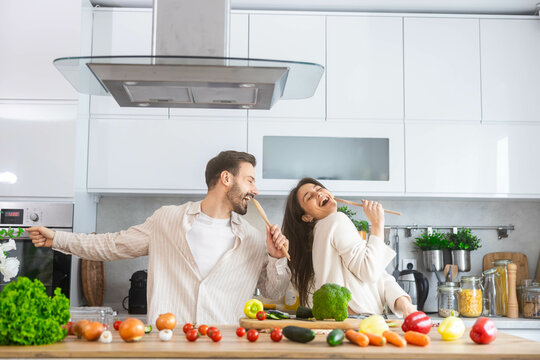 A vibrant kitchen scene depicts a couple joyfully cooking and enjoying each other's company amidst fresh ingredients.