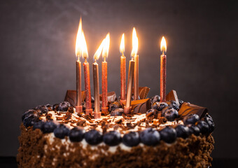 delicious chocolate cake with candles and blueberries for a holiday or birthday.