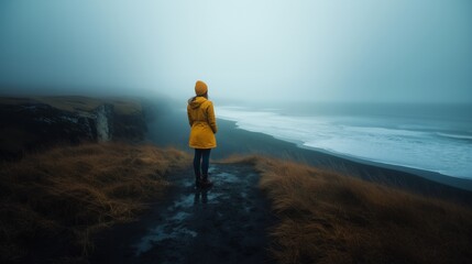 Woman in Yellow Coat Gazing at Foggy Coastline, A moment of contemplation.