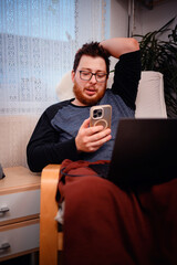Relaxed Man Looking at Smartphone While Sitting at Home