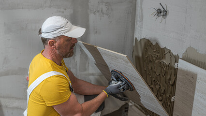 Tiling with large format tiles. A tiler placing a tile held by a tile suction cups.