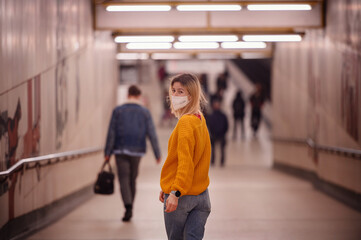 Obraz premium Woman in Yellow Sweater Wearing a Mask in a Subway Tunnel