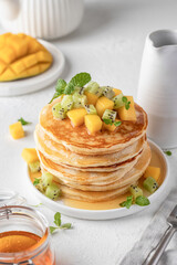 Pancakes with fruit and honey in plate on white background. Delicious dessert for Maslenitsa or Pancake Day. Healthy breakfast