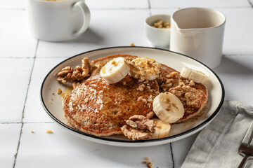 Healthy oatmeal pancakes with banana, nuts and honey on white tile background. Morning food breakfast concept. Pancake day or Maslenitsa recipe