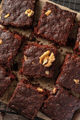 Chocolate brownie cake dessert with nuts on baking rack on dark background top view