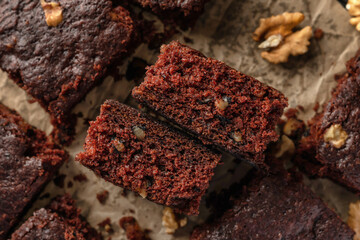 Chocolate brownie cake dessert with nuts on baking rack on dark background top view. Texture