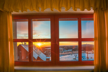 A picturesque sunrise beams warm light through a multi-paneled window while snow covers the ground, creating a peaceful atmosphere