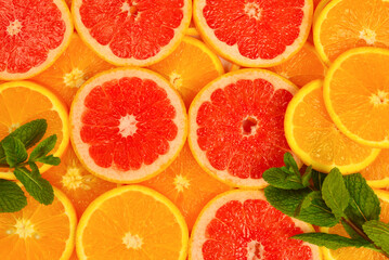 Slices of oranges and a grapefruits and mint as a background.