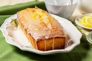 Aromatic lemon cake, covered with sugar icing and sprinkled with zest, served with tea.