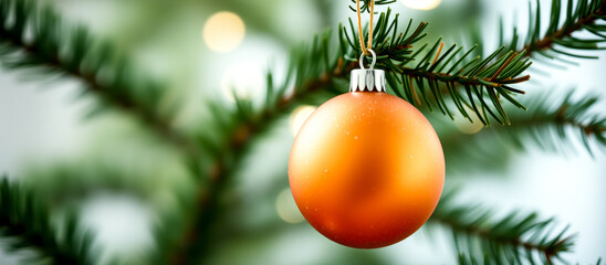 Obraz premium shiny christmas tree bauble hangs from a lush green pine branch.