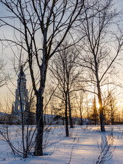 Snowy field with trees and a church in the background