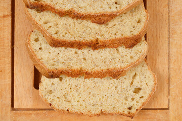 Slices of homemade bread with chia seeds are arranged on a wooden cutting board, showcasing the texture and healthy ingredients