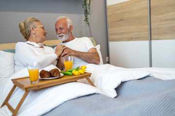 Senior Couple Enjoying Breakfast in Bed With Fresh Orange Juice
