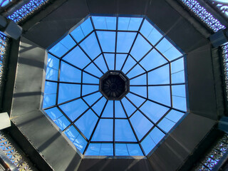 An iron gazebo with a glass ceiling on a blue sky background