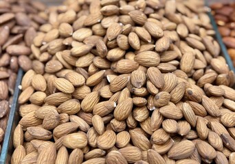 Roasted delicious inshell almonds with spices in large quantities for sale at the vegetable market. Close-up