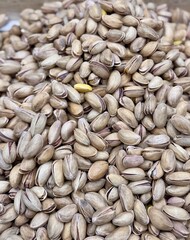 A lot of fried selected clean delicious pistachios for sale in a box at a local specialty market. Close-up