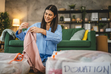 One woman caucasian adult at home choose clothes for charity donation