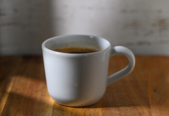 Warm coffee cup sitting on a wooden table with soft light in a cozy corner