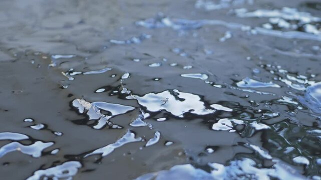 Layer of bituminous waterproofing putty is spread on rough concrete surface. This black, viscous putty is used in construction to create a waterproof barrier, protecting buildings from water.