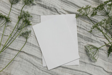 Wedding, birthday desktop mock-up. Blank greeting card, envelope on beige linen table cloth...