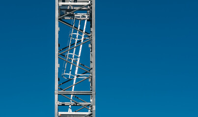 Steel Lattice Tower with a Safety Ladder Against a Clear Blue Sky
