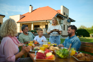 Happy family having lunch together in backyard of their home