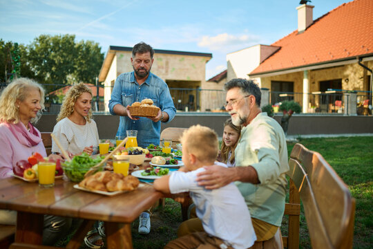 Happy family enjoying meal together at table outdoors in backyard,
