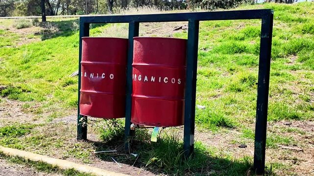 Two red barrels with the word organicos written on them. The barrels are on a grassy hill